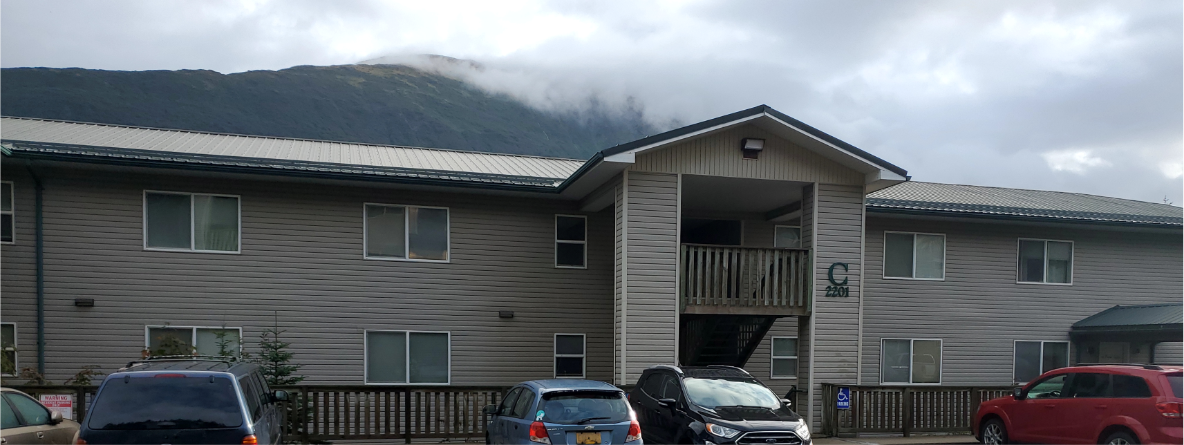a building with a mountain in the background and cars parked in front